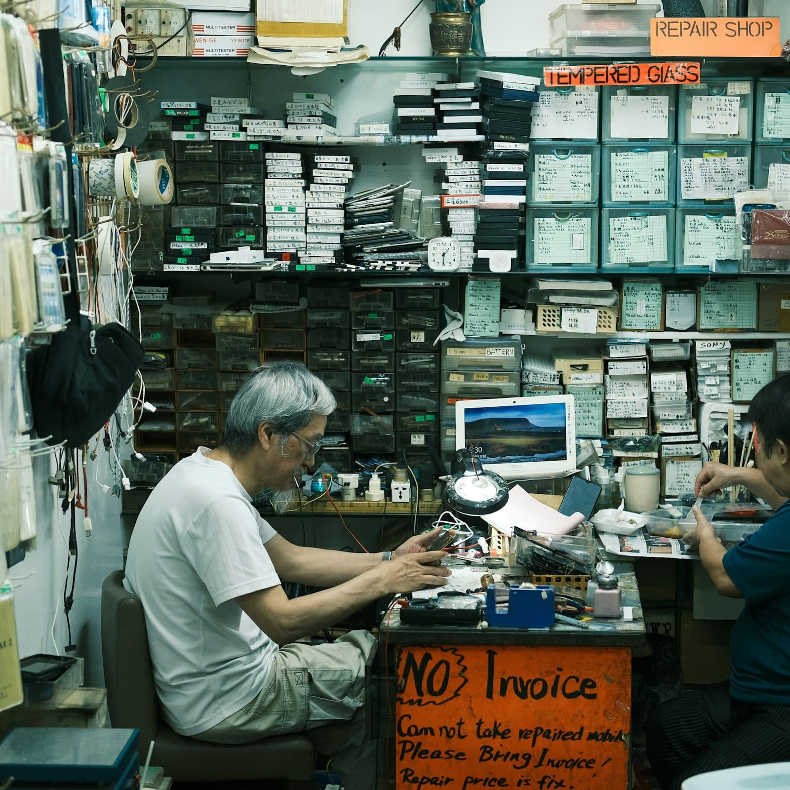 Technicians repairing phones at a busy repair shop counter